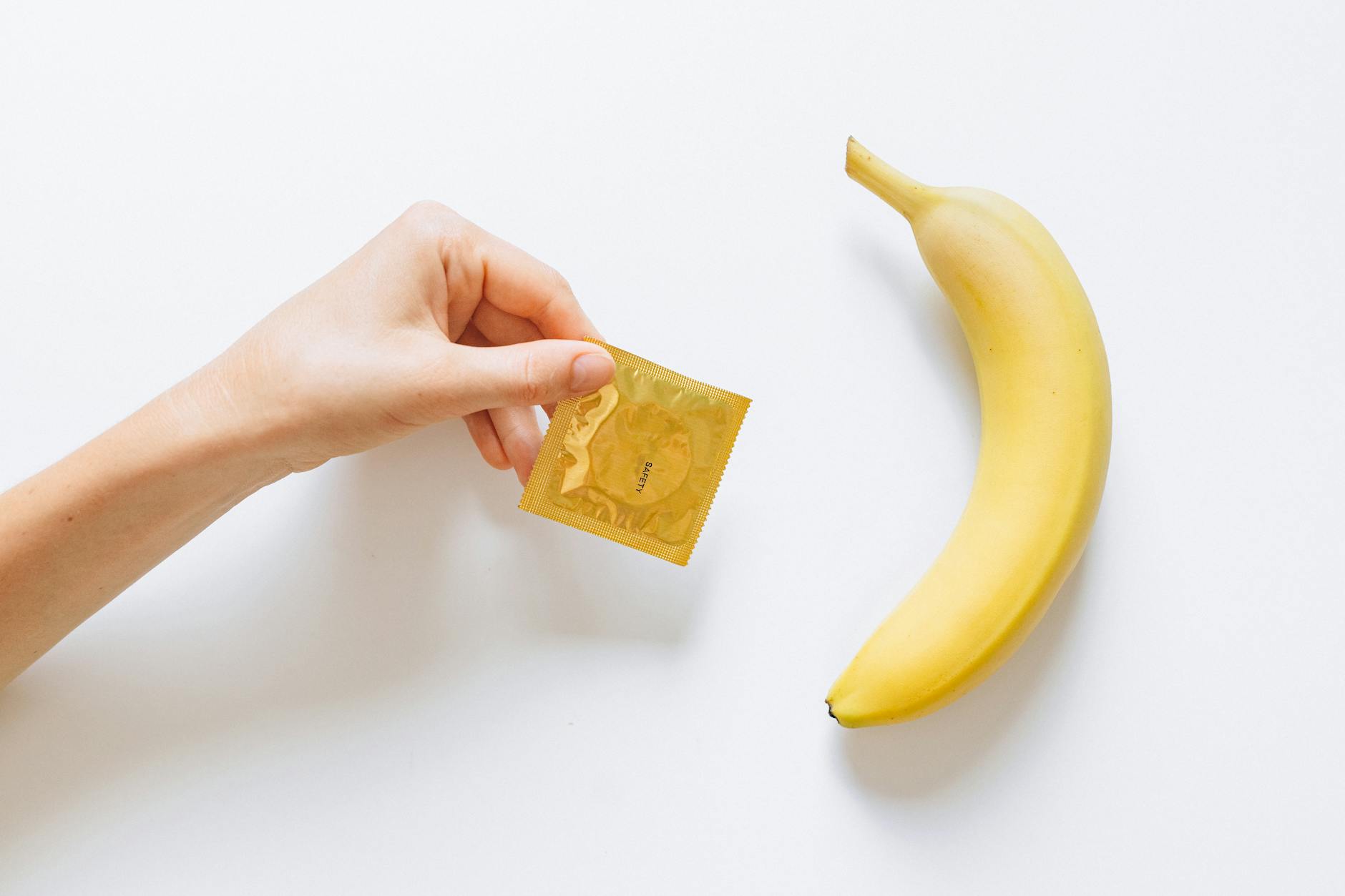 person holding condom next to banana
